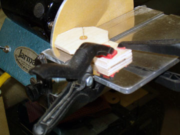 The base and plug are clamped to the disk sander.  The plug is rotated to shape it to a perfect circle.