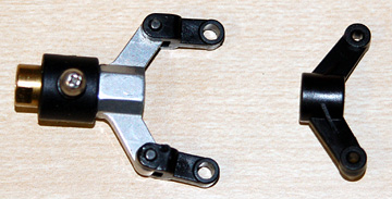 Stock plastic tail pitch control fork (right) with upgrade metal fork (left).