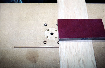 Attach a guide to the router table and use a sanding block to push the board through the cutter.