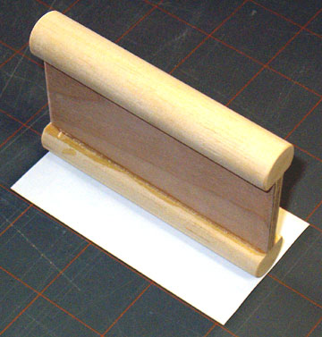 Center the dowel on the tape-backed sandpaper and roll the paper on to the dowel.