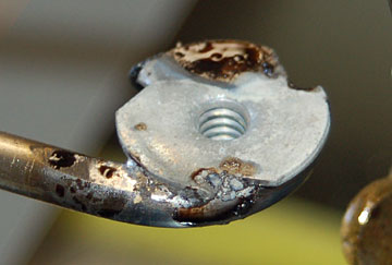 Drop the blind nut in place on the molten solder.